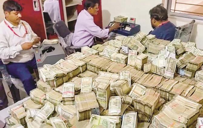 Officials counting the amount seized in ED proceedings. Photo: PTI
