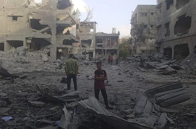 Palestinians stand near rubble in Gaza. Image: X