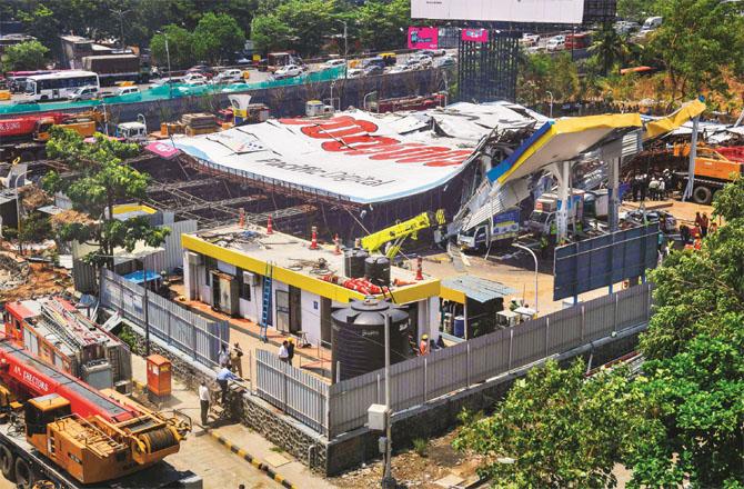 Attempts are being made to remove the fallen hoarding at Chedangar petrol pump. Photo: INN
