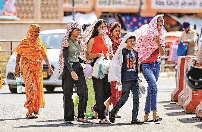 Some people can be seen wrapping themselves in clothes to avoid the heat. Photo: PTI.