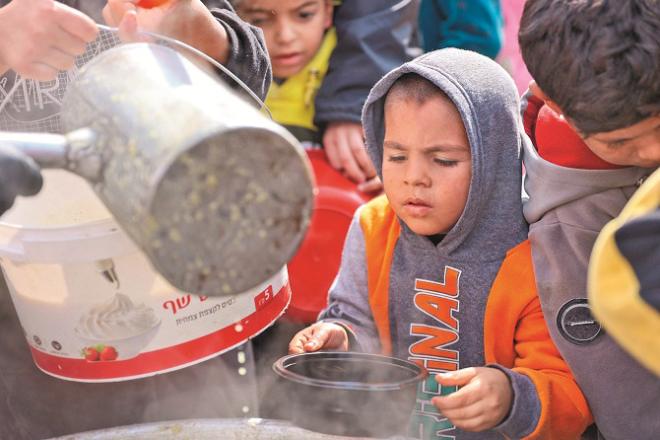 Children can be seen at a food distribution stall in a refugee camp in Gaza. Photo: INN
