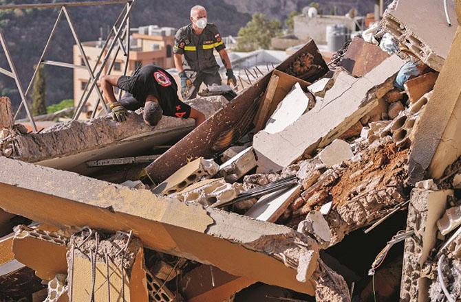 A social worker searches for people buried under the rubble in Barja, Lebanon. Photo: INN