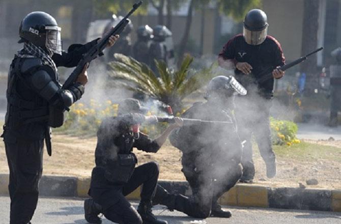 Police officers firing tear gas shells at protesters. Photo: PTI