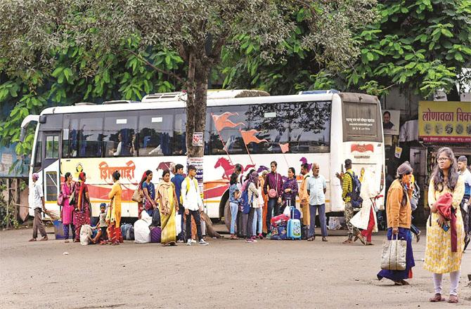 Passengers wait for a ride with their belongings at Pune ST depot (Photo PTI)