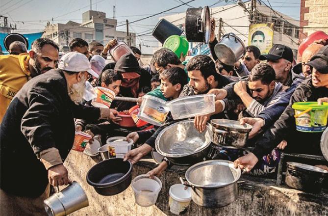 Displaced Palestinians can be seen taking food at the UN relief center. Photo: INN
