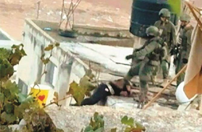 Israeli soldiers push the body of a martyred Palestinian on the roof of the house. Photo: INN
