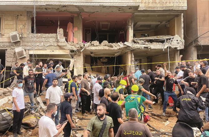 Locals near a building destroyed by an Israeli army airstrike in Beirut. Photo: INN