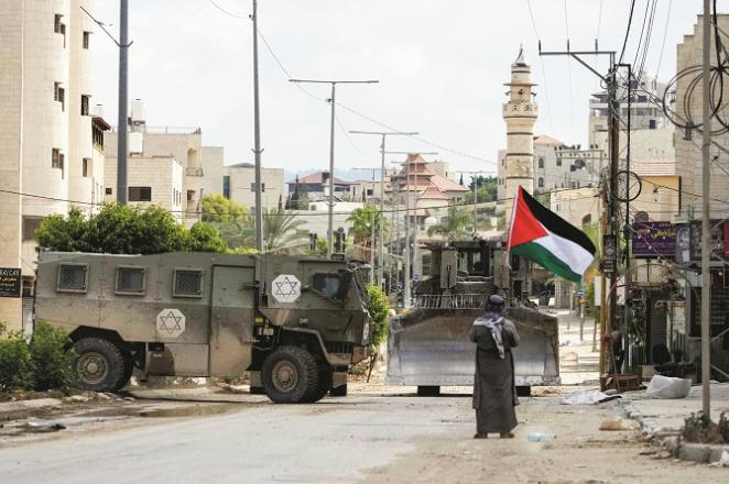 Palestinian volunteer Khairy Hanoun protests in front of Israeli armored vehicles in Tulkarm. Photo: INN