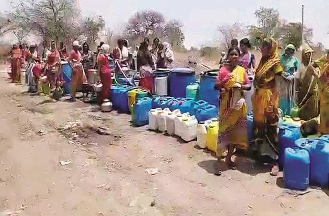 Village women wait for a water tanker in the scorching sun.