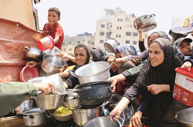 Hungry civilians carry containers to receive food at a food distribution center in Gaza. Photo: INN