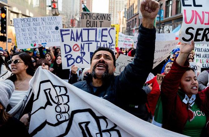 Protesters hold a placard in support of immigrants. Photo: X
