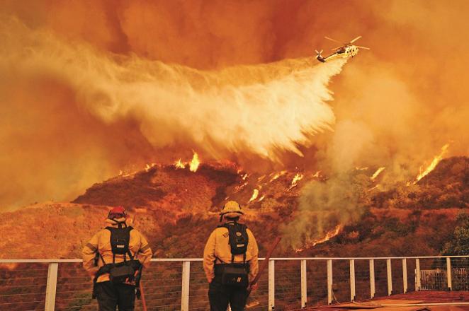A large swath of California was still under fire on Monday, with firefighters watching from helicopters to spray water. Photo: INN