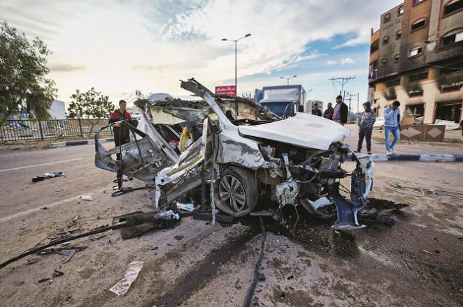People look at a damaged car as a result of Israeli bombing in Gaza. Photo: AP/PTI