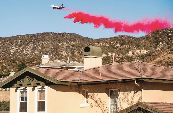 The photo shows a plane flying over the hills of Altadena spraying fire retardant. Photo: PTI.