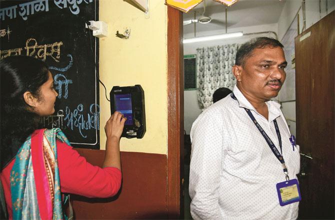 A municipal school employee is taking biometric attendance. (File photo)
