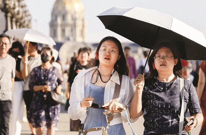 Tourists can be seen using umbrellas to escape the heat in Paris, the capital of France. Photo: INN