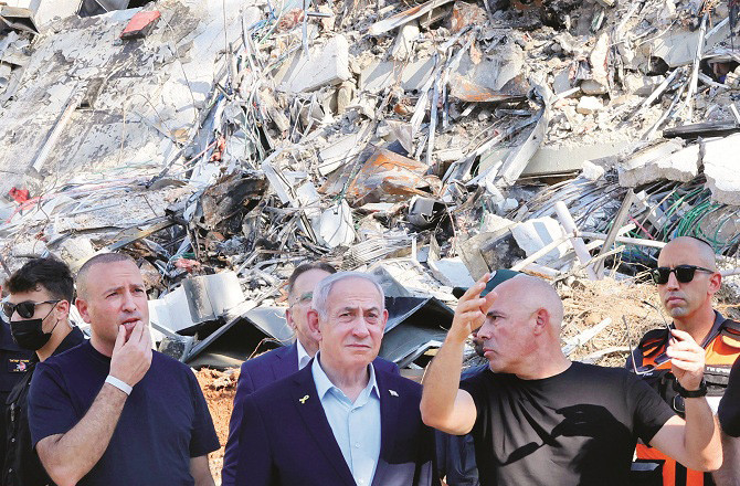 Israeli Prime Minister Netanyahu looks dejected as he stands next to a building damaged in an Iranian attack. Photo: AP/PTI