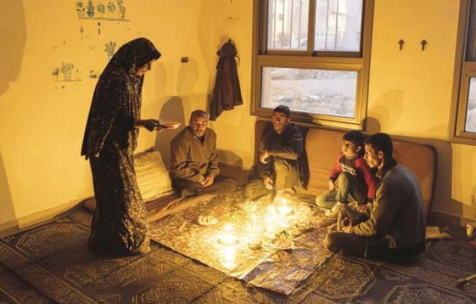 A family in Gaza breaks their fast by candlelight after the power supply was cut off. Photo: INN