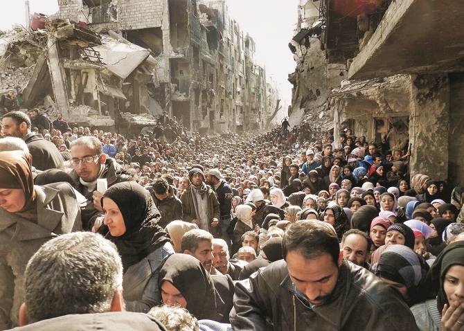 تصویر کا نام: Humanitarian crisis، ہیومینی ٹیرین کرائسیز، &nbsp;فوٹو گرافر: یو این آر ڈبلیو اے، کب کھینچی گئی؟: ۲۰۱۴ء، تفصیل: زیر نظر تصویر دمشق، شام کے ایک مشہور علاقے یرموک کی ہے جہاں تارکین وطن کی لمبی بھیڑ دیکھی جاسکتی ہے۔ یرموک ایک غیرسرکاری پناہ گزین کیمپ ہے کیونکہ ۱۹۶۰ء میں یو این آر ڈبلیو اے نے شامی حکومت کی درخواست پر اسے تسلیم کرنے سے انکار کر دیا تھا۔ یہاں زیادہ تر فلسطینیوں نے پناہ لی ہے۔ قبل ازیں یہ شام میں فلسطینیوں کیلئے سب سے بڑا پناہ گزین کیمپ تھا۔ شام میں ۴؍ لاکھ سے زائد فلسطینیوں نے پناہ لی ہے۔