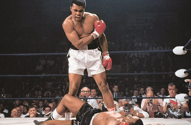 تصویر کا نام: Muhammad Ali Vs Sonny Liston، محمد علی بمقابلہ سنی لسٹن، فوٹو گرافر: نیل لیفر،کب کھینچی گئی؟: ۱۹۶۵ء، تفصیل: زیر نظر تصویر میں ۲۵؍ مئی ۱۹۶۵ء میں ڈومینک ایرینا، لیوئسٹں، میئن ،امریکہ میں &rsquo;&rsquo;ورلڈ ہیوی ویٹ ٹائٹل فائٹ&lsquo;&lsquo; میں پہلے راؤنڈ میں سنی لسٹن کو ہرانے کے بعد محمد علی کا ردعمل دکھایا گیا ہے۔محمد علی مکہ باز ہونے کے علاوہ اداکار، گلوکار، شاعراور مصنف تھے۔ انہوں نے مکے بازی کے ۵۶؍ مقابلے جیتے تھے۔ انہیں بنگلہ دیش کی اعزازی شہریت عطا کی گئی تھی۔