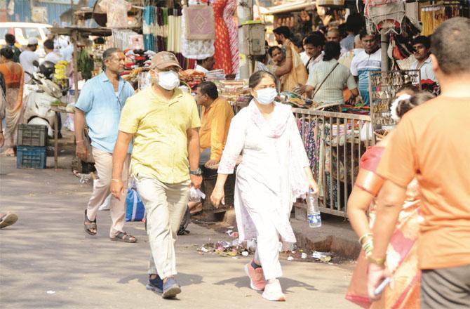 People are walking around in crowded areas wearing masks as a precaution.