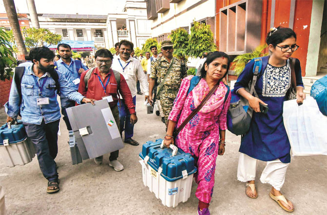 Polling officers carrying their EVMs to the polling station. (Photo: PTI)