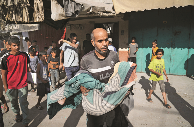 The body of Hassan Nasr (12), who was killed in an Israeli strike in central Gaza on Thursday, can be seen being carried by his children. Photo: INN