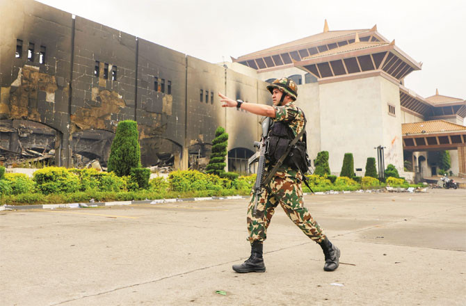 Military personnel are stationed outside the Nepal Federal Parliament. In the background, the parliament wall can be seen, which has been blackened by arson. (PTI)
